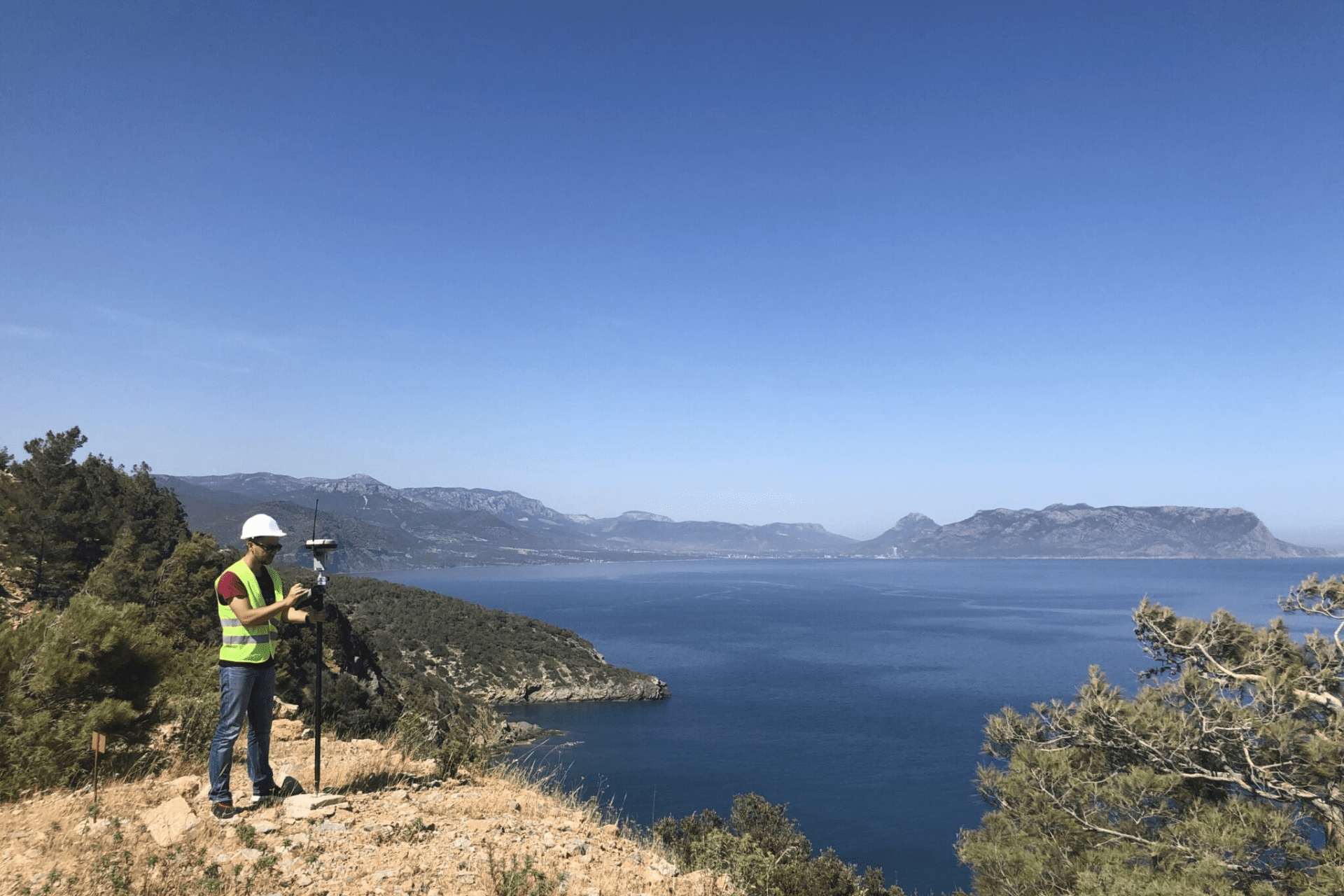 Surveyor on overlook measures with transit and laptop