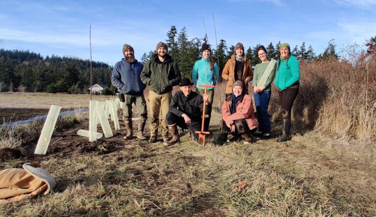 A group of conservationists posing for a group photo. They were planting trees in a tree row.